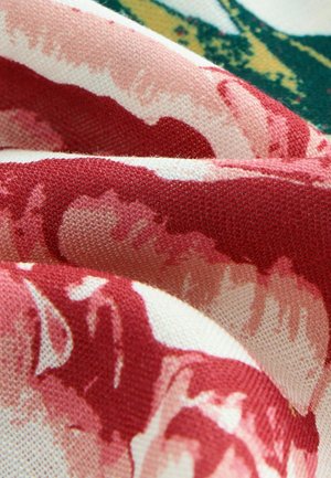 Un material textil cu un model floral, prezentând trandafiri roșii mari pe un fundal roz deschis, accentuat de frunziș verde, cu un finisaj moale și texturat.