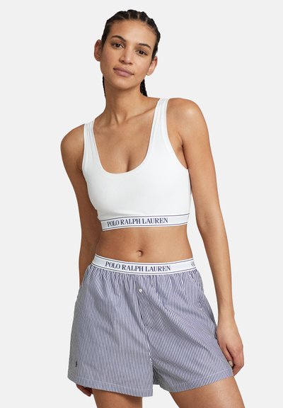 Witte crop top met een ronde hals en marineblauw gestreepte shorts met een gebrandmerkte tailleband. Gladde stof, comfortabele pasvorm en verticale strepen.