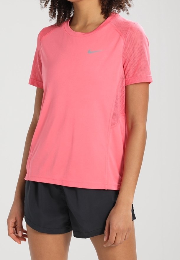 Rosa kortärmad träningsskjorta med nätaccenter, rund halsringning och en silverfärgad Nike-logga på övre vänster sida. Matchas med svarta shorts.