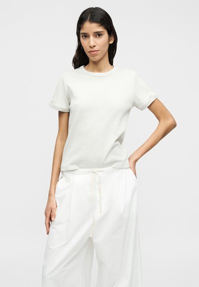 Ανοιχτό γκρι κοντομάνικη μπλούζα με στρογγυλή λαιμόκοψη, με μαλακή υφή και άνετη εφαρμογή, συνδυασμένη με άνετο λευκό παντελόνι με κορδόνι στη μέση.