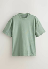Light green cotton t-shirt with a round neck, short sleeves, and a loose fit. Texture appears smooth with minimal seams and no patterns.