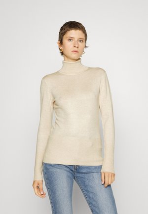 Beige turtleneck sweater made of soft material, featuring long sleeves and a fitted design. Paired with light blue jeans.