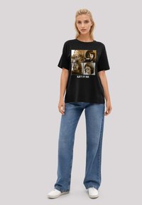 Black t-shirt featuring a collage of four sepia-toned images on the front and the text "LET IT BE." Worn with light blue wide-leg jeans.