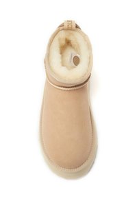 Beige enkelboot met een zachte, donzige binnenvoering, een gladde suède buitenkant, een ronde neus en subtiele stikdetails.