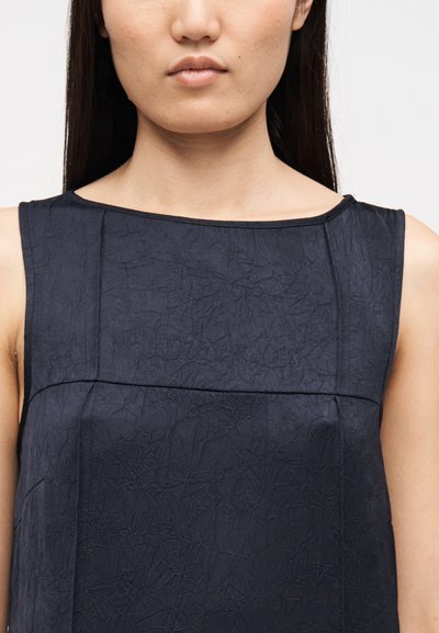 Tumesinine varrukateta kleit tekstuurse pinnaga, nelinurkalusega ja peente õmblustega. Disainitud lõõgastunud istuvusega.