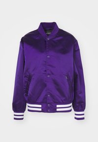 Paarse satijnen bomberjack met een knoopsluiting, twee zijzakken en witte gestreepte ribgebreide manchetten en zoom. Heeft een gladde textuur.