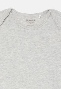 Svijetlosiva Huggies babywear bodi za 18-mjesečne bebe s kratkim rukavima i izrezom na ramenima, položen ravno na bijeloj pozadini.