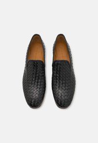 Chaussures noires en cuir tressé à enfiler avec un intérieur en cuir lisse tan. Présentent un bout arrondi et des détails de couture minimalistes.