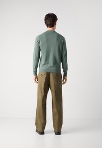 Mint green knitted sweater with a round neckline, paired with light brown wide-leg trousers. Both items feature a smooth texture and simple design.