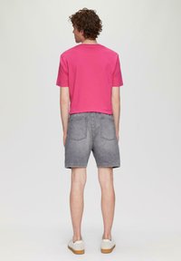 Różowa koszulka z krótkim rękawem o luźnym kroju, w zestawieniu z szortami z szarego denimu. Posiada dwie tylne kieszenie oraz proste białe trampki.