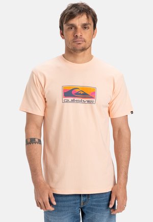 Helles Pfirsichfarbene Baumwoll-T-Shirt mit einem bunten Quiksilver-Logo-Design auf der Brust. Kurze Ärmel und eine lockere Passform.