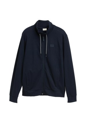 Donkerblauwe ritssluitingjas gemaakt van textuurstof. Heeft een hoge kraag, trekkoord en zijzakken. Eenvoudig ontwerp zonder zichtbare patronen.