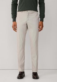 Pantalones chinos beige claro con un corte recto clásico, fabricados con suave tela de algodón, que cuentan con cierre de botón y bolsillos laterales.