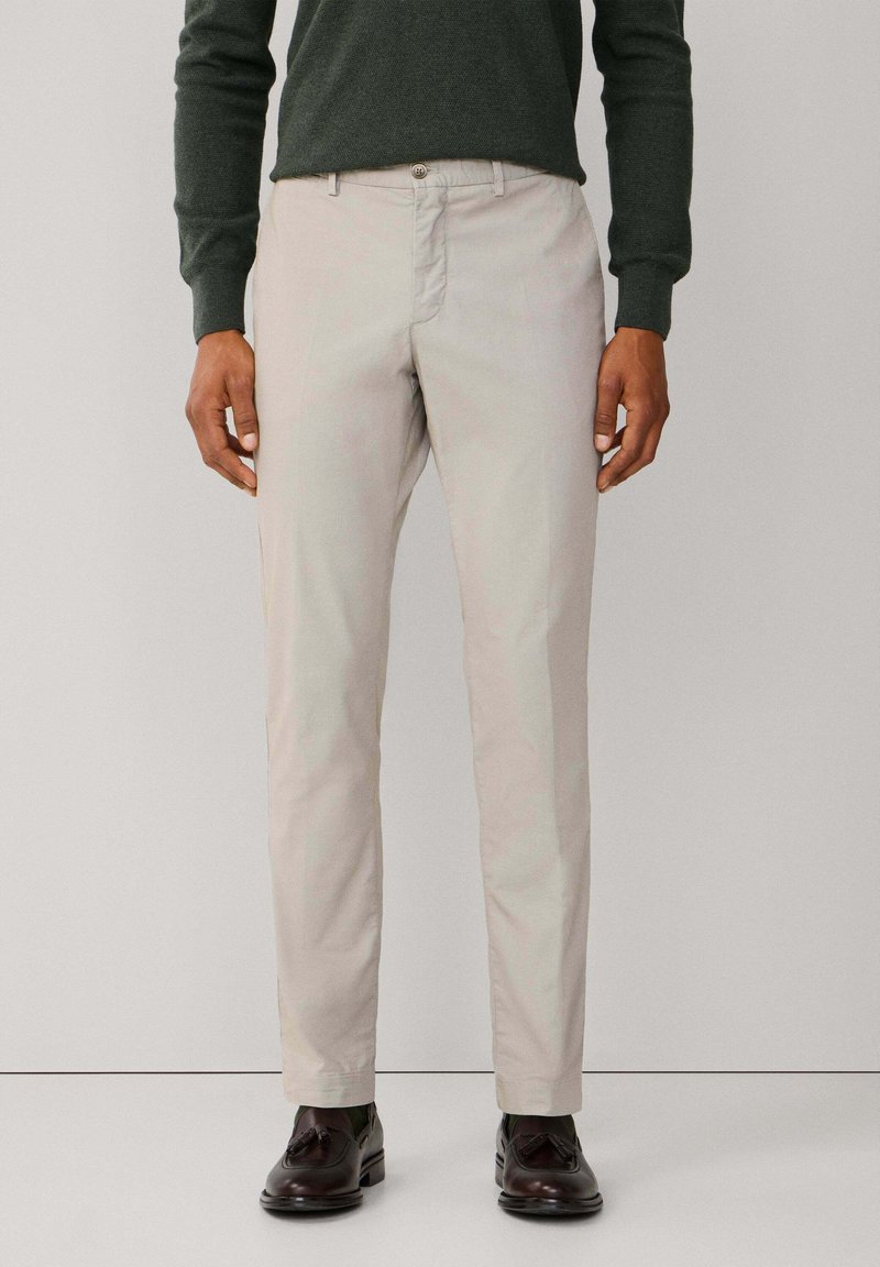 Pantalones chinos beige claro con un corte recto clásico, fabricados con suave tela de algodón, que cuentan con cierre de botón y bolsillos laterales.