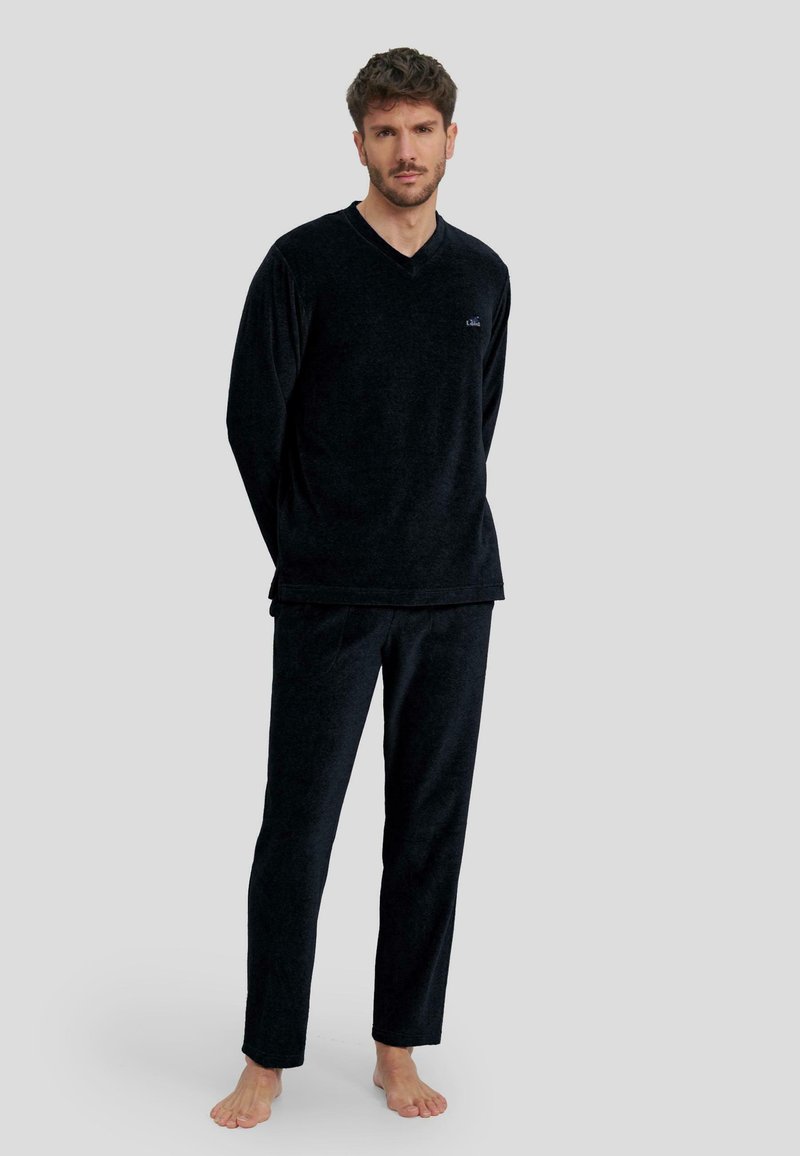 Conjunto de loungewear de terciopelo negro que incluye una camiseta de cuello en V de manga larga y pantalones a juego, con una textura suave y un corte relajado.