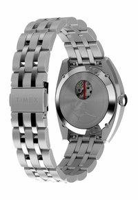 Reloj de acero inoxidable plateado con una pulsera gruesa de eslabones. La caja angular muestra un movimiento visible a través de una parte trasera transparente.