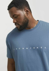 Lyseblå bomulds t-shirt med rund hals og korte ærmer, prydet med "JACK & JONES" trykt i hvidt henover brystet i en moderne skrifttype.