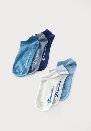 Sechs Paar flache Champion-Socken in Blau, Grau, Navy, Weiß und Hellblau auf weißem Hintergrund angeordnet.