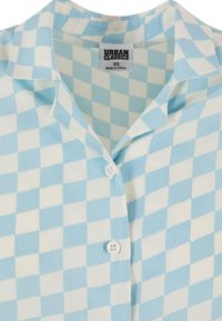 Chemise à manches courtes à carreaux bleu clair et blanc avec un col, ornée de boutons blancs et d'une étiquette à l'intérieur. Texture de tissu douce.