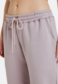Lila sweatpants met een trekkoord in de taille, zachte textuur en zijzakken. Voorzien van een subtiele geborduurde logo aan de voorkant.