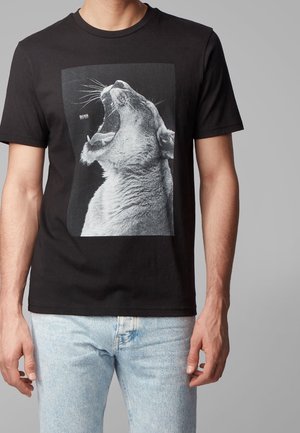 Schwarzes Baumwoll-T-Shirt mit einer großen Grafik eines brüllenden Löwen in Monochrom. Klassisches Rundhalsausschnitt-Design mit kurzen Ärmeln.