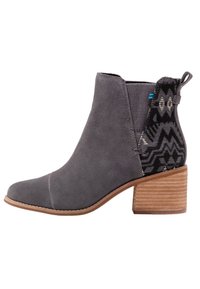 Botines de ante gris con un panel textil estampado en negro y dorado metálico, con un tacón de madera apilado y un lado elástico.