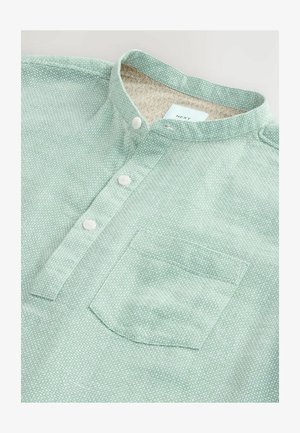 Helles grünes, strukturiertes Button-up-Hemd mit Mandarin-Kragen, drei weißen Knöpfen und einer Brusttasche; gefüttert mit einem gemusterten Stoff.