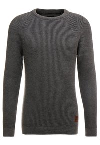 Pull gris tricoté avec encolure ras du cou, manches longues, et poignets et ourlet côtelés. Présente un petit patch logo sur le côté inférieur.