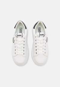 Vita sneakers med slät läderöverdel, rund tå, svart hälaccent, sex öglor och logotyp på tungan. Gummisula med texturerat grepp.