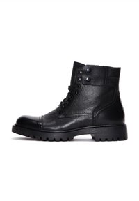 Botas de cuero negras hasta el tobillo con acabado texturizado, punta redonda, diseño con cordones y dos botones a presión en la parte superior. Suela de goma gruesa con relieve.
