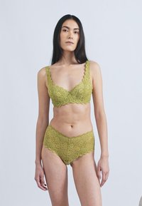 Pitsist pesukomplekt oliivirohelises toonis, millel on lainelised servad, lillemustrid ja pehme tekstuur. Komplektis on rinnahoidja ja sobivad aluspüksid.