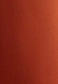 Close-up van oranje textiel met een diagonaal geribbeld patroon en een consistent geweven structuur.