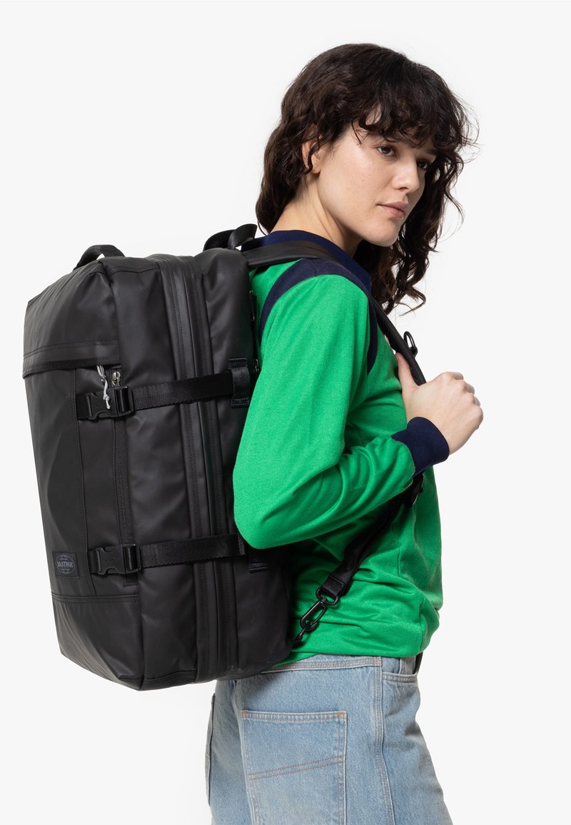 Zaino nero realizzato in materiale resistente, dotato di spallacci regolabili, forma rettangolare e numerosi scomparti con zip.