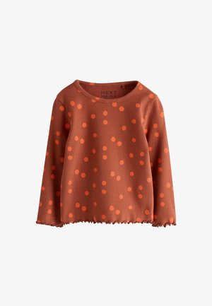 Langærmet rust-orange ribbet top med klare orange polkaprikker og bølget kant, rund halsudskæring.