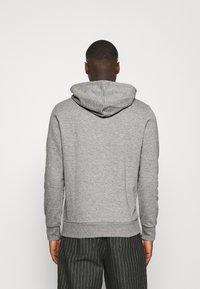Felpa grigia in cotone con cappuccio regolabile, polsini e orlo a coste. Presenta una trama uniforme; nessun motivo o dettaglio aggiuntivo visibile.