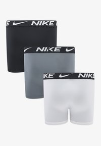 Tri para boksačkih gaćica marke Nike u crnoj, sivoj i bijeloj boji, s elastičnim pojasom na kojem se nalazi logo "NIKE", glatkim tkanjem i tijesnim krojem.