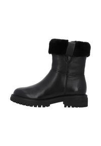 Bota tobillo de cuero negro con un suave cuello forrado de piel, suela de goma resistente y una marca sutil. Cuenta con punta redondeada y una lengüeta para tirar.