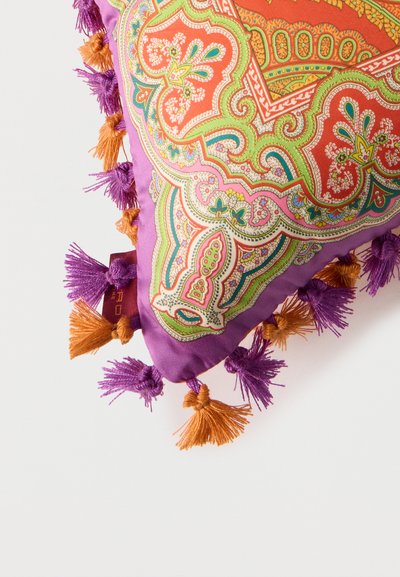 Coussin décoratif violet avec des motifs paisley complexes orange, verts et roses, bordé de glands violets et orange alternés.