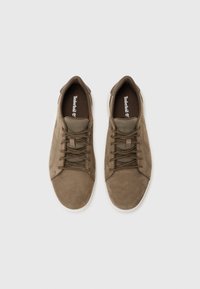 Sapatilhas de camurça castanhas com detalhes em malha, bico redondo e atacadores combinantes. Apresentam uma sola de borracha branca e o logotipo da Timberland na palmilha.