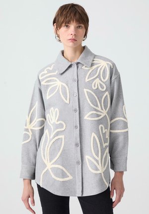 Gray button-up shirt made of soft fabric, featuring white floral embroidery. The collar is wide, and the fit is relaxed with long sleeves.