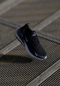 Svart träningsskor med en överdel i mesh, Air Max-dämpning och en vit Nike-swoosh-logga. Har en texturerad tunga och vadderad krage.