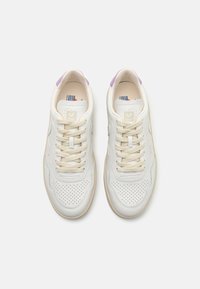 Vita lädersneakers med perforerat tåparti, beige snörningar och lavendelfärgad detaljer på hälkappen. Gräddfärgad gummisula.