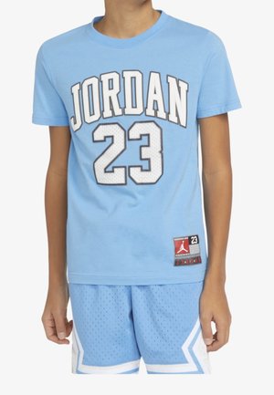 Enfant portant un t-shirt Jordan bleu clair avec le numéro 23 et un short de sport assorti perforé.