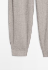 Lichtgrijze tapered broek van een textuurstof, met een manchettenzoom en strakke lijnen voor een gestructureerd silhouet.