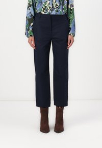 Marineblauwe broek met een rechte snit, met een gladde textuur en een voorplooien, gecombineerd met bruine leren enkellaarsjes.