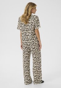 Leopard print loungewear set in beige and black. Short-sleeved top and wide-leg pants made of soft fabric with a smooth texture.