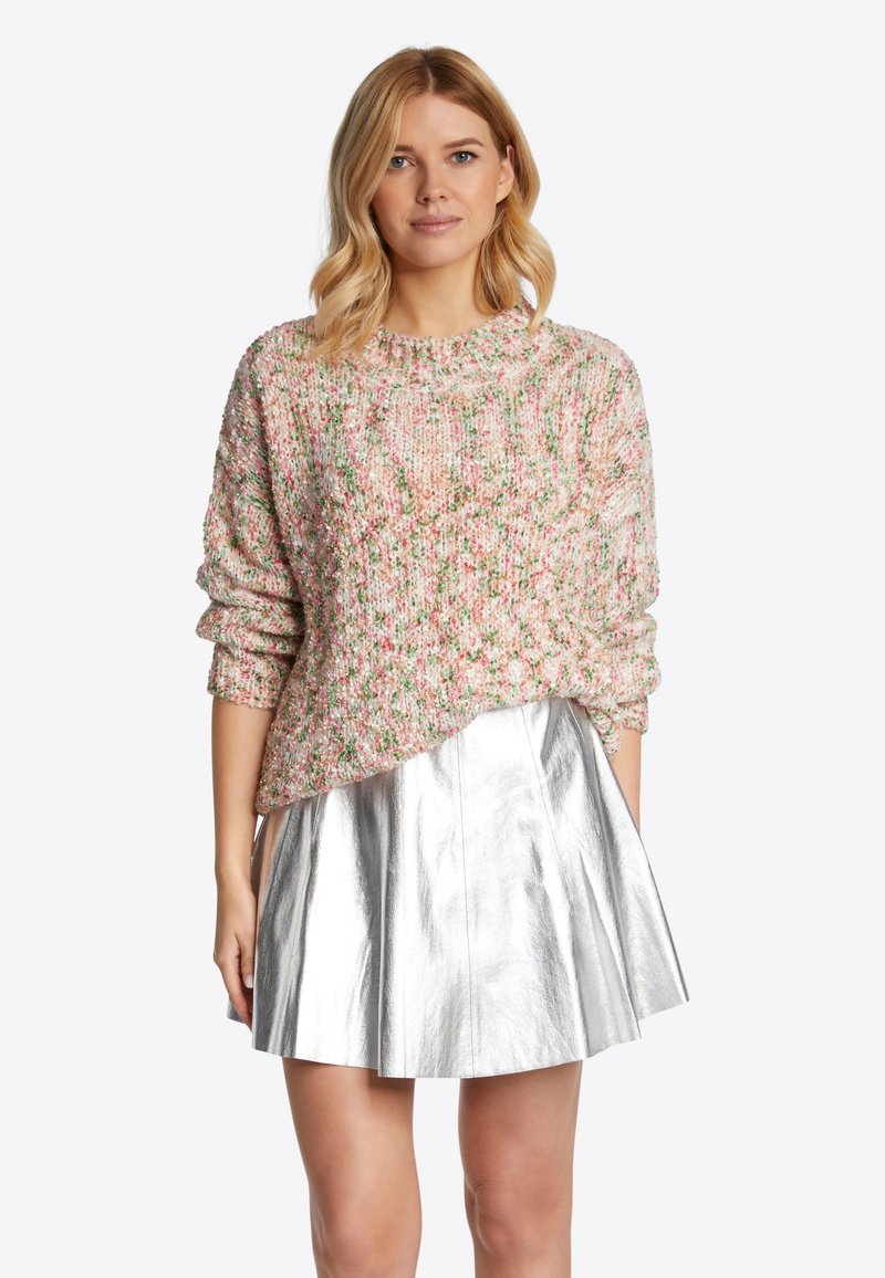 Rosa und grün strukturierter Strickpullover mit Rundhalsausschnitt, kombiniert mit einem metallisch silbernen A-Linien-Rock, der ein glänzendes Finish und Falten aufweist.