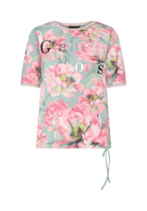 Chemise à manches courtes avec un grand motif floral rose sur fond bleu clair et texte décoratif "Glamorous" à l'avant, détail noué à l'ourlet.