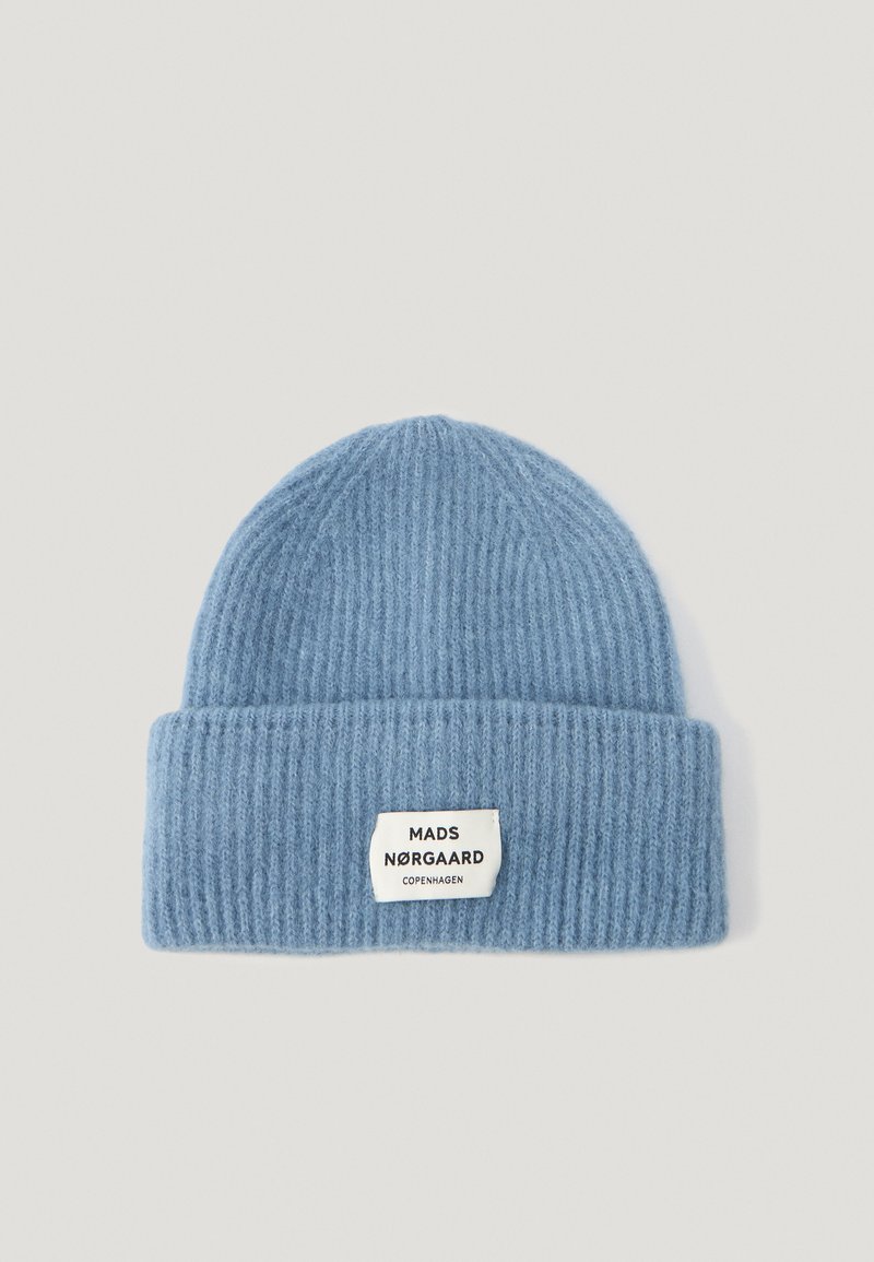 Heledad sinine soonikkoostee müts volditud äärega ning kudumisega ruudukujuline silt, millel on "MADS NØRGAARD COPENHAGEN." Pehme tekstuur.