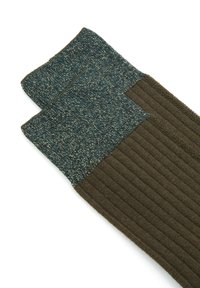 Calze lavorate a maglia con una parte inferiore a coste di un verde scuro e un risvolto in teal strutturato. Il risvolto presenta un motivo maculato con filamenti metallici.